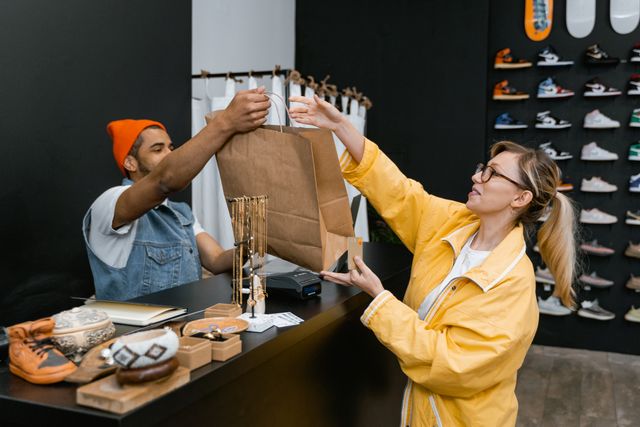 A shop assistant handing a bag to a customer at checkout